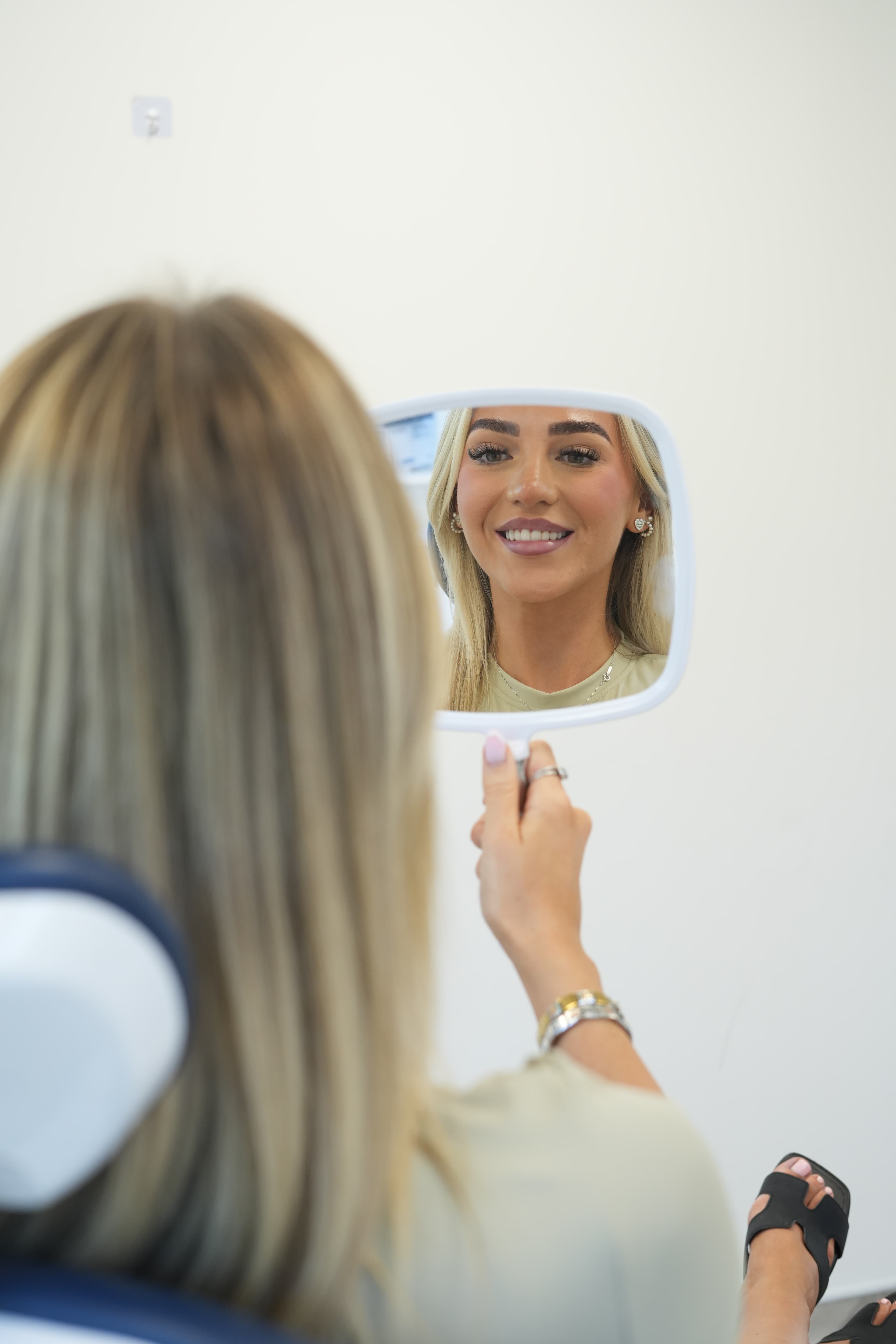 Patient seeing her new smile in the mirror at Space Dental
